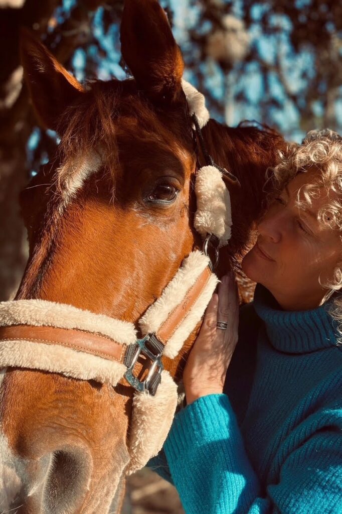 Femme contre la tête d'un cheval alezan, soins énergétiques et équilibre du cheval à Narbonne