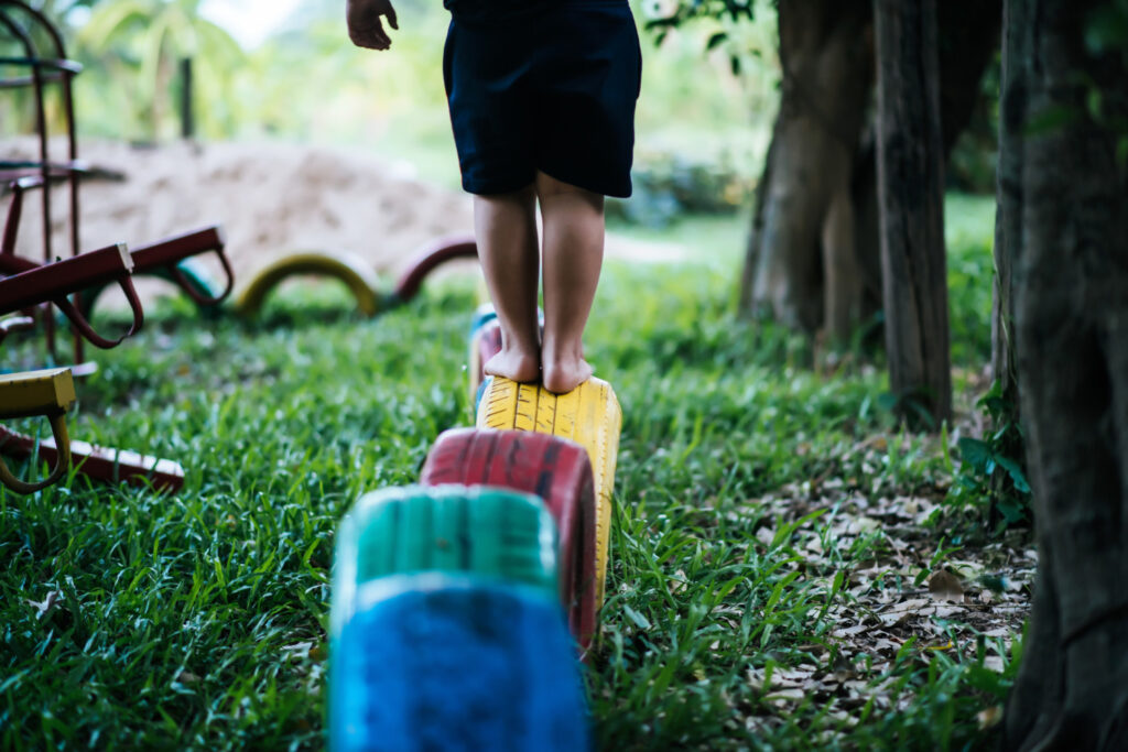 Enfant marchant dans l'herbe avec son cartable, sophrologie pour enfants et bien-être à Narbonne